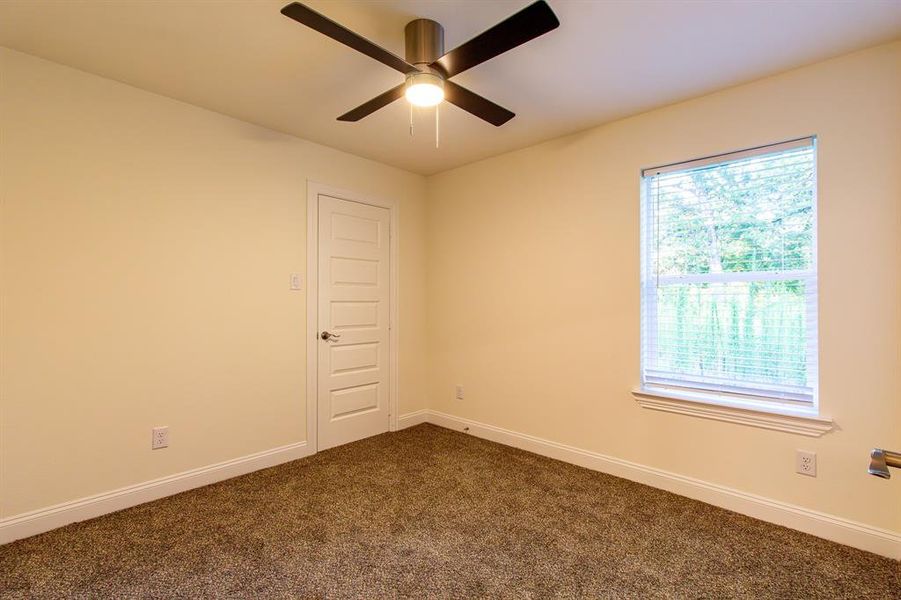 Spare room with dark colored carpet and a ceiling fan Spare room with dark colored carpet and a ceiling fan