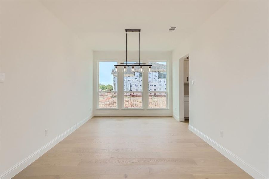 Unfurnished dining area featuring an inviting chandelier and hardwood / wood-style flooring