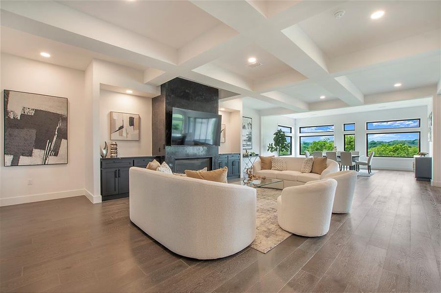 Living room featuring beamed ceiling, coffered ceiling, a large fireplace, and dark hardwood / wood-style flooring