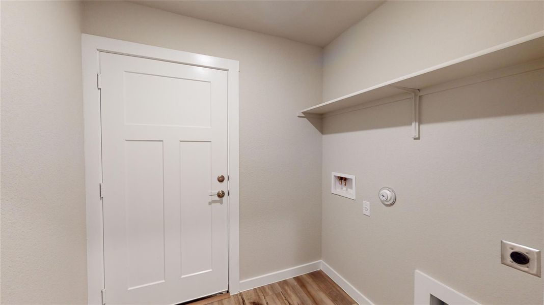 Functional laundry room featuring a convenient wall-mounted shelf for storage. Functional laundry room featuring a convenient wall-mounted shelf for storage.