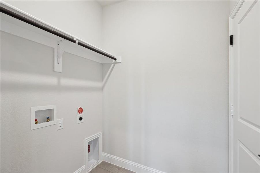 Washroom with hookup for an electric dryer, washer hookup, baseboards, and light tile patterned floors