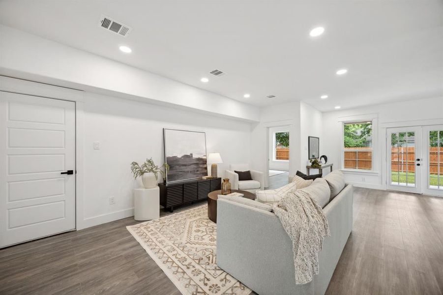 Living room with wood-style floors, open to the kitchen, dining area and back patio