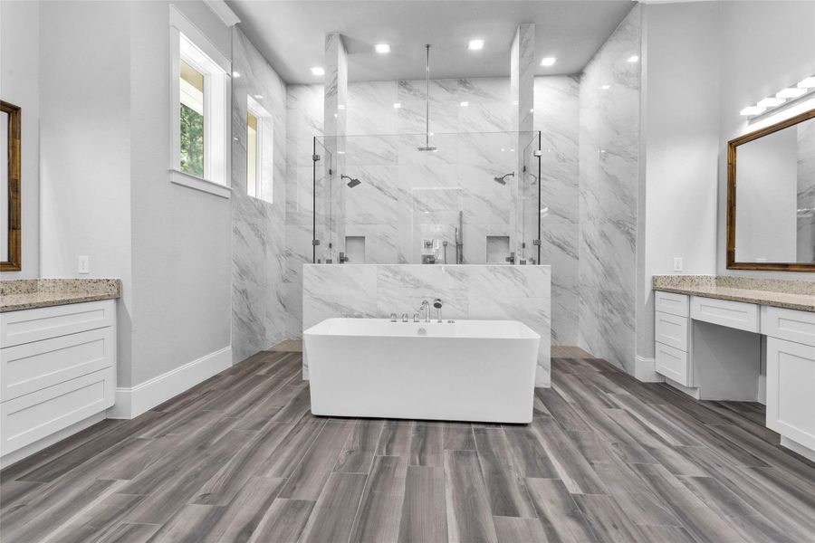 The spacious Primary En Suite Bathroom features a spa-inspired standalone bath nestled in front of a dramatic oversized shower with frameless glass.