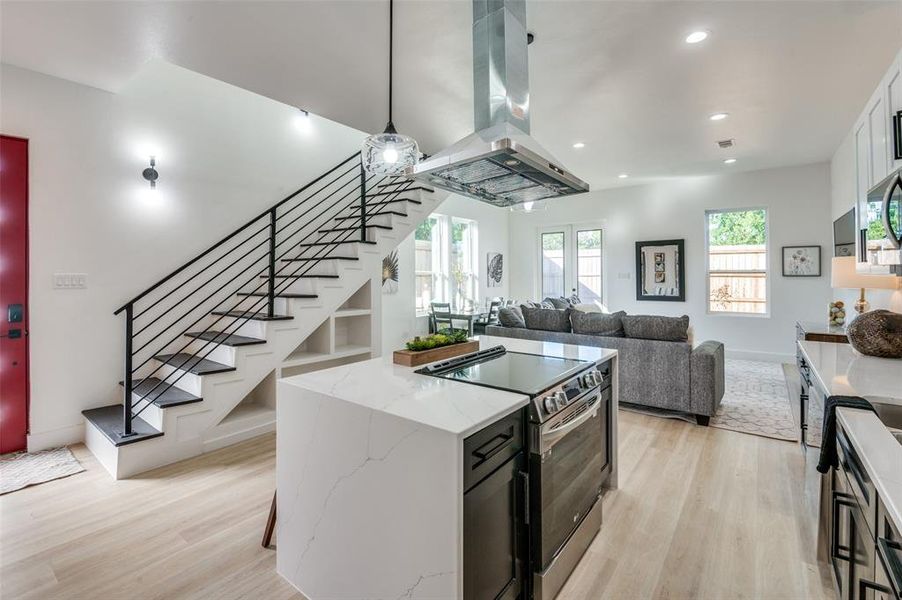 Kitchen featuring white cabinetry, light wood-type flooring, electric range, and island range hood