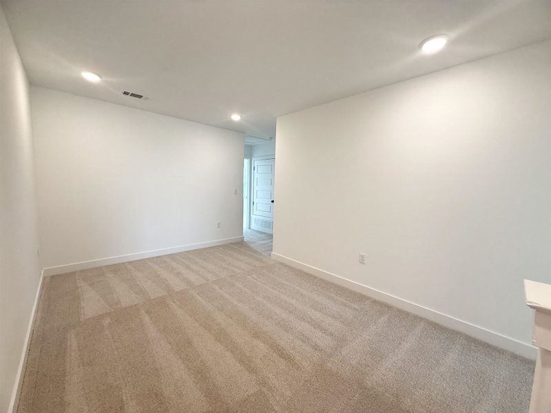 Empty room with light carpet and recessed lighting