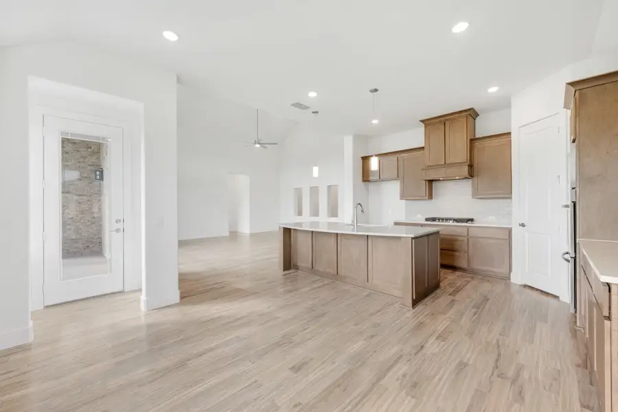 Open kitchen with wood cabinets, center island, and light wood floors open to living area Open kitchen with wood cabinets, center island, and light wood floors open to living area