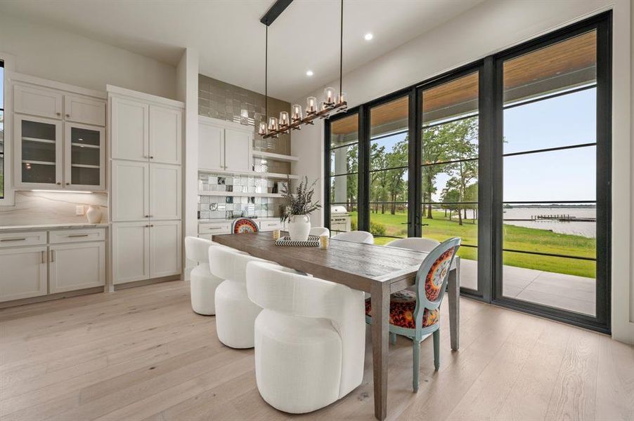 Dining room with light wood-style floors, a water view, recessed lighting, and a chandelier Dining room with light wood-style floors, a water view, recessed lighting, and a chandelier