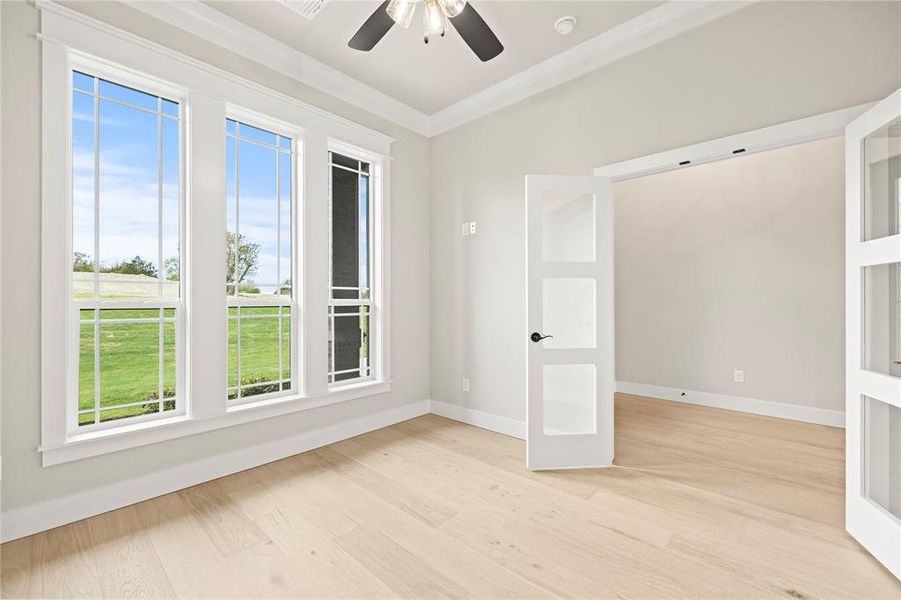 Empty room with light wood finished floors, ornamental molding, and french doors Empty room with light wood finished floors, ornamental molding, and french doors