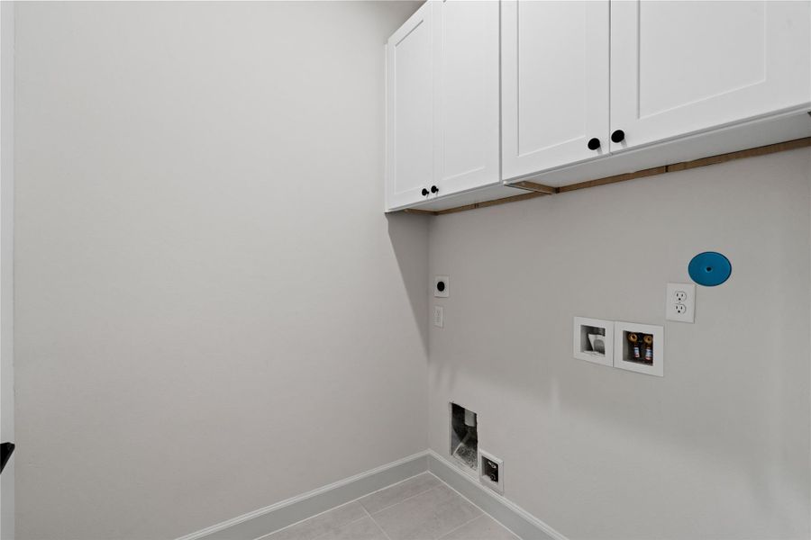 A generously sized laundry room with built-in cabinets that help keep everything neatly stored.