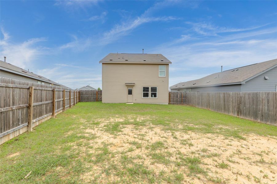 A spacious backyard enclosed by a wooden fence provides ample outdoor living space.
