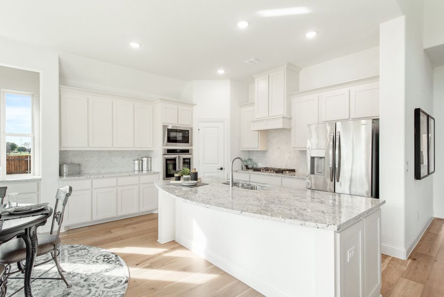 Kitchen with white cabinets, granite island, stainless steel appliances, and light hardwood floors Kitchen with white cabinets, granite island, stainless steel appliances, and light hardwood floors
