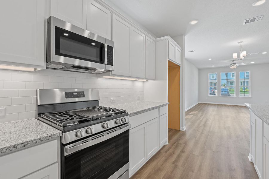 Kitchen with appliances with stainless steel finishes, light wood-style flooring, white cabinets, backsplash, and recessed lighting Kitchen with appliances with stainless steel finishes, light wood-style flooring, white cabinets, backsplash, and recessed lighting