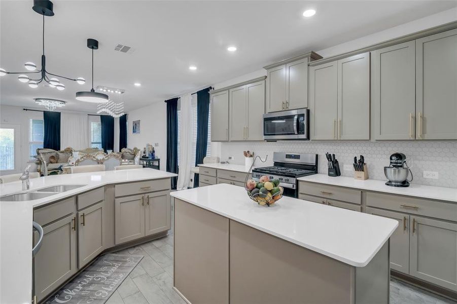 Kitchen with a center island, sink, gray cabinets, a notable chandelier, and stainless steel appliances