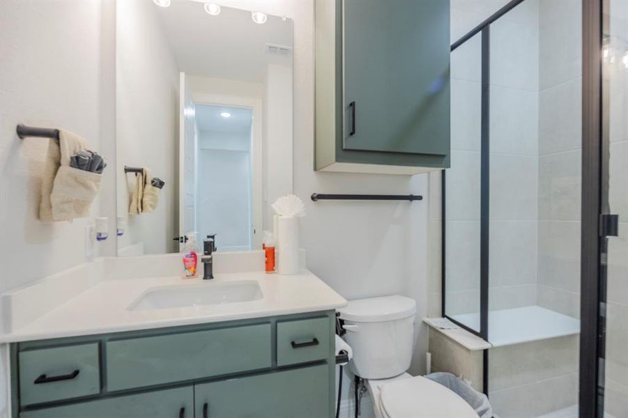 Full bathroom featuring visible vents, a shower stall, vanity, and toilet