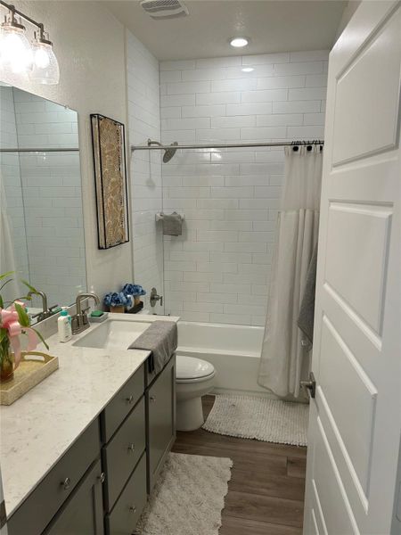 Full bath featuring shower / bath combo, dark wood-style floors, and vanity Full bath featuring shower / bath combo, dark wood-style floors, and vanity