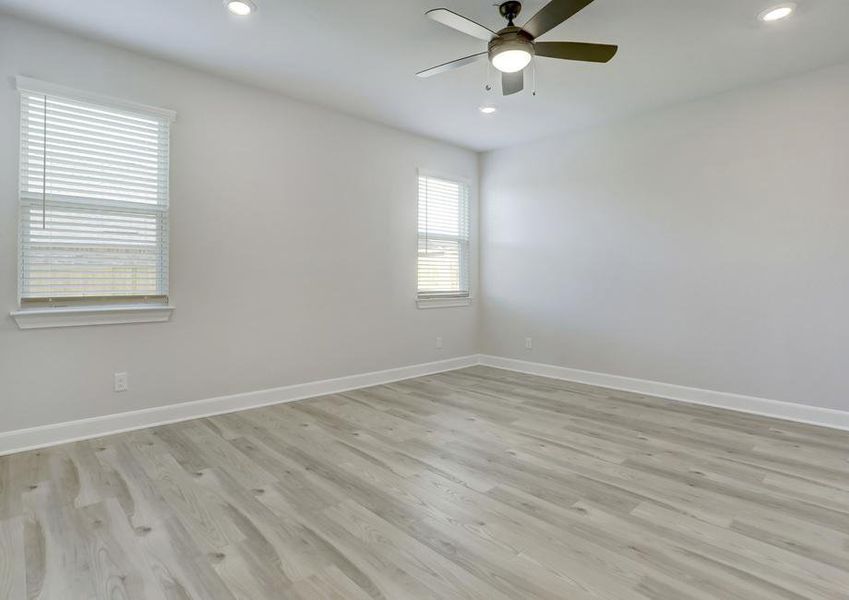 Spacious master bedroom with a ceiling fan and two windows.