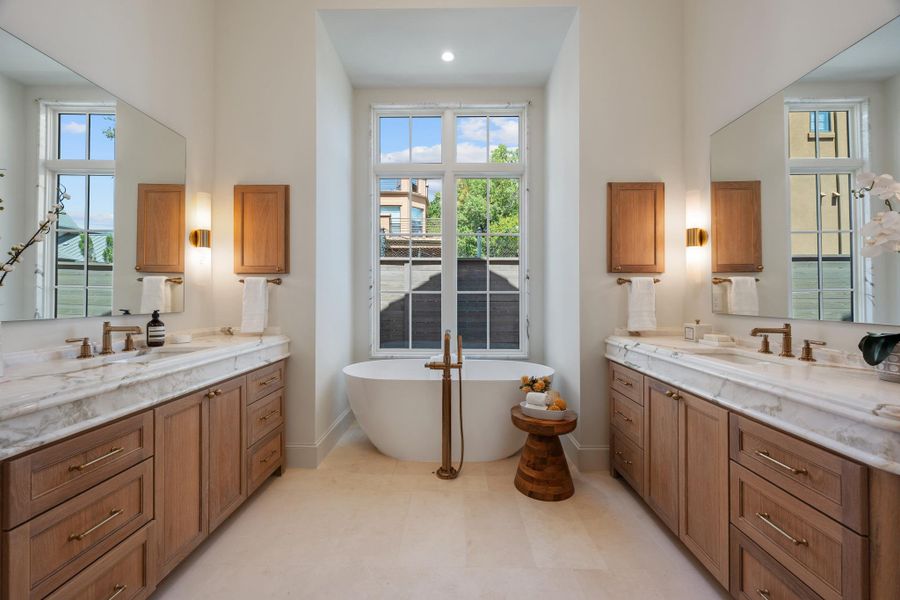 Double vanities frame a freestanding soaking tub situated beneath a tall window.