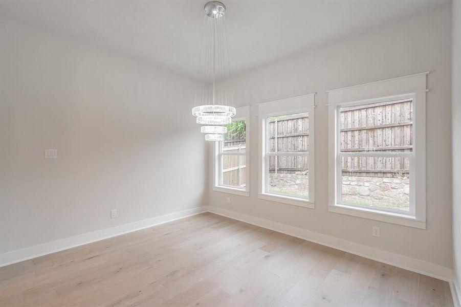 Unfurnished dining area featuring light wood finished floors and a chandelier