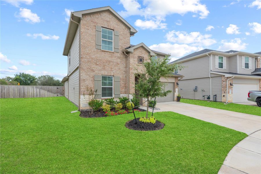Front elevation showing the brick facade, two-car garage and wide concrete driveway.