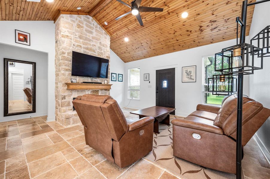 Designed for comfort and everyday living, this inviting space features soaring wood ceilings, a floor-to-ceiling stone fireplace, and large windows that bring in abundant natural light. The open layout and warm finishes make the room feel both spacious and welcoming.