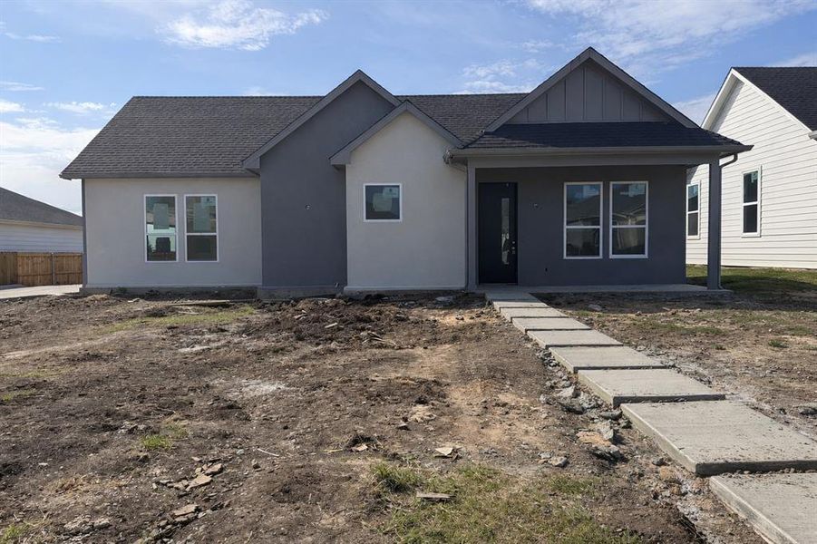 View of front facade featuring board and batten siding, roof with shingles, a porch, and stucco siding