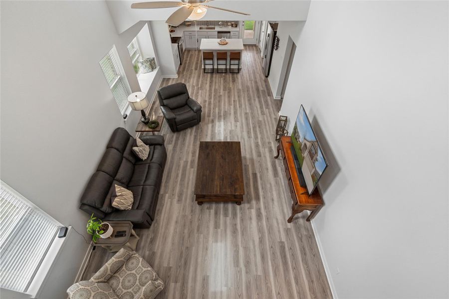 Living room featuring wood finished floors, ceiling fan, a high ceiling, and baseboards Living room featuring wood finished floors, ceiling fan, a high ceiling, and baseboards