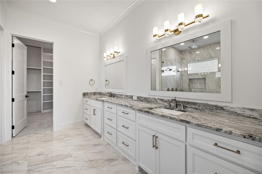 Bathroom with light marble finish flooring, double vanity, a marble finish shower, ornamental molding, and a spacious closet Bathroom with light marble finish flooring, double vanity, a marble finish shower, ornamental molding, and a spacious closet