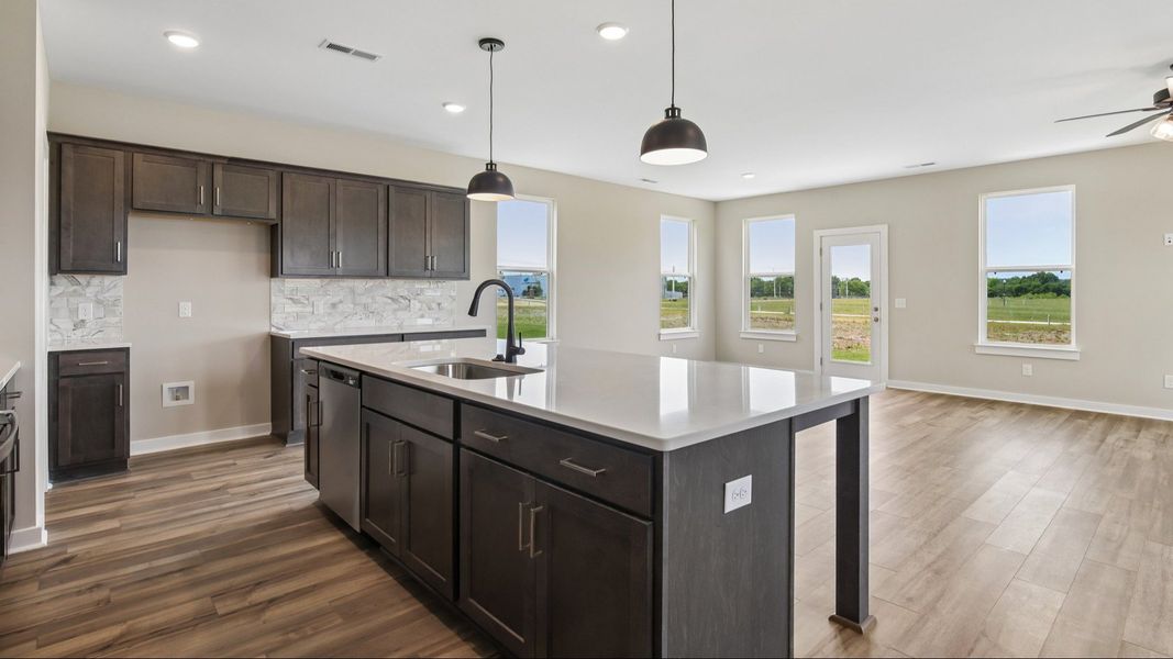 Kitchen with dark cabinetry, quartz countertops, and view of gathering room