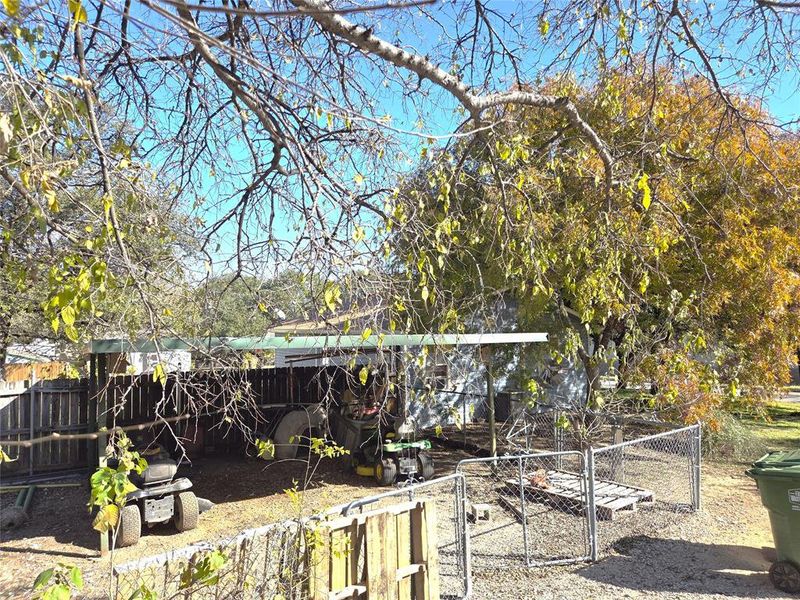 Another fenced area featuring a carport.