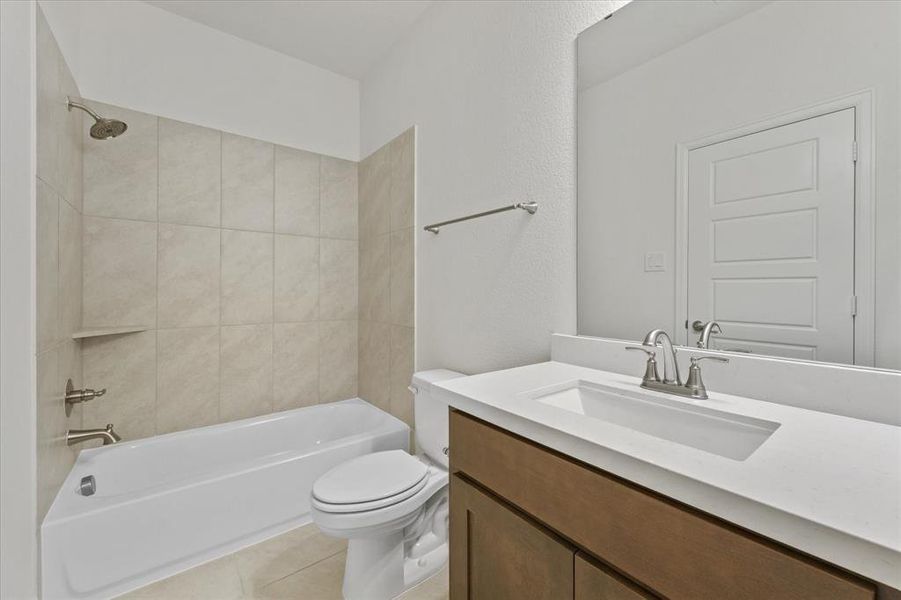 Bathroom featuring shower / washtub combination, vanity, light tile patterned flooring, and a textured wall