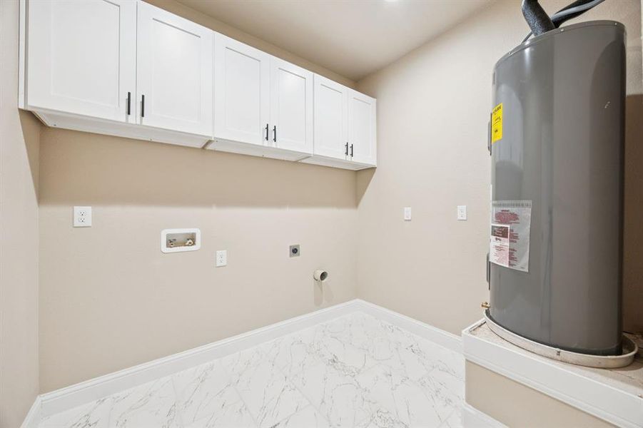 Washroom with electric water heater, light marble finish flooring, hookup for an electric dryer, cabinet space, and hookup for a washing machine Washroom with electric water heater, light marble finish flooring, hookup for an electric dryer, cabinet space, and hookup for a washing machine