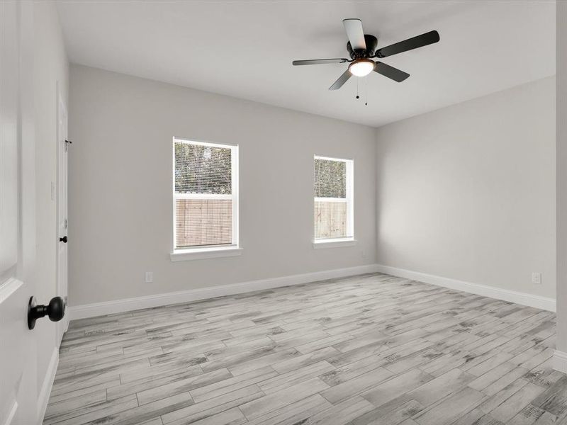 Empty room featuring ceiling fan, plenty of natural light, and light hardwood / wood-style flooring