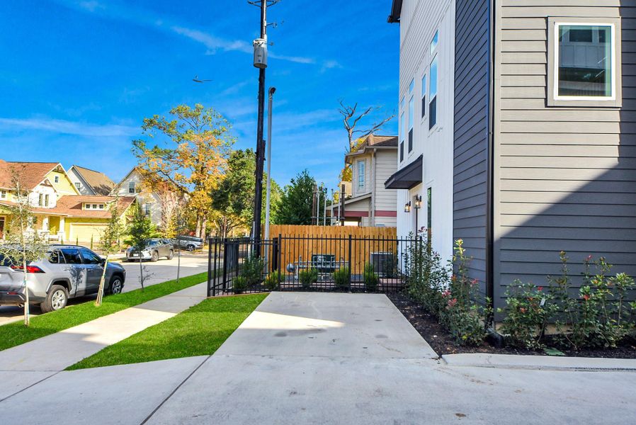 The multi-story townhouse design offers both style and function, with large windows and a fenced yard. The driveway adds convenience while the overall look is sleek and modern.