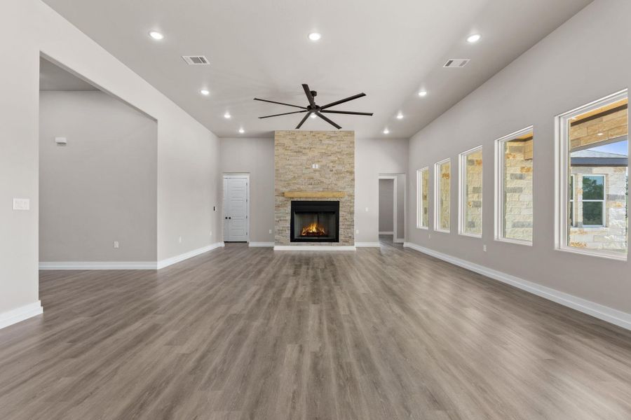 A spacious great room showcases a floor-to-ceiling stone fireplace, recessed lighting, and ample natural light. A spacious great room showcases a floor-to-ceiling stone fireplace, recessed lighting, and ample natural light.