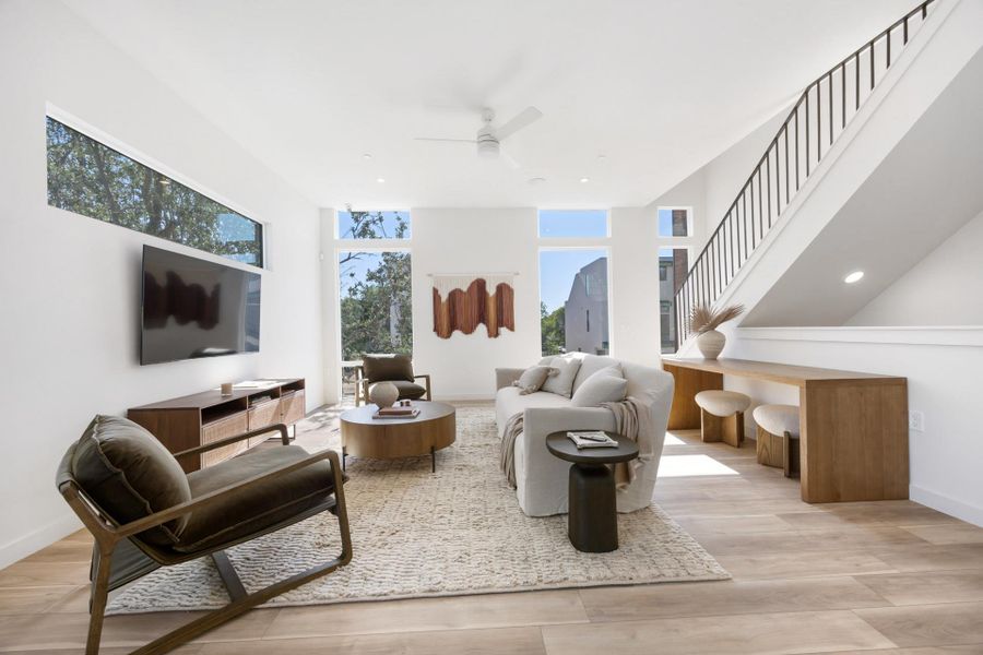 Living room with stairs, light wood-type flooring, ceiling fan, and recessed lighting Living room with stairs, light wood-type flooring, ceiling fan, and recessed lighting