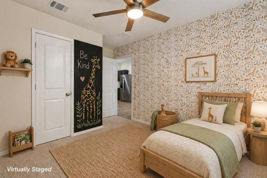 Bedroom featuring a ceiling fan with light fixture, patterned wallpaper accent wall, light-toned carpeting, and a chalkboard wall panel Bedroom featuring a ceiling fan with light fixture, patterned wallpaper accent wall, light-toned carpeting, and a chalkboard wall panel