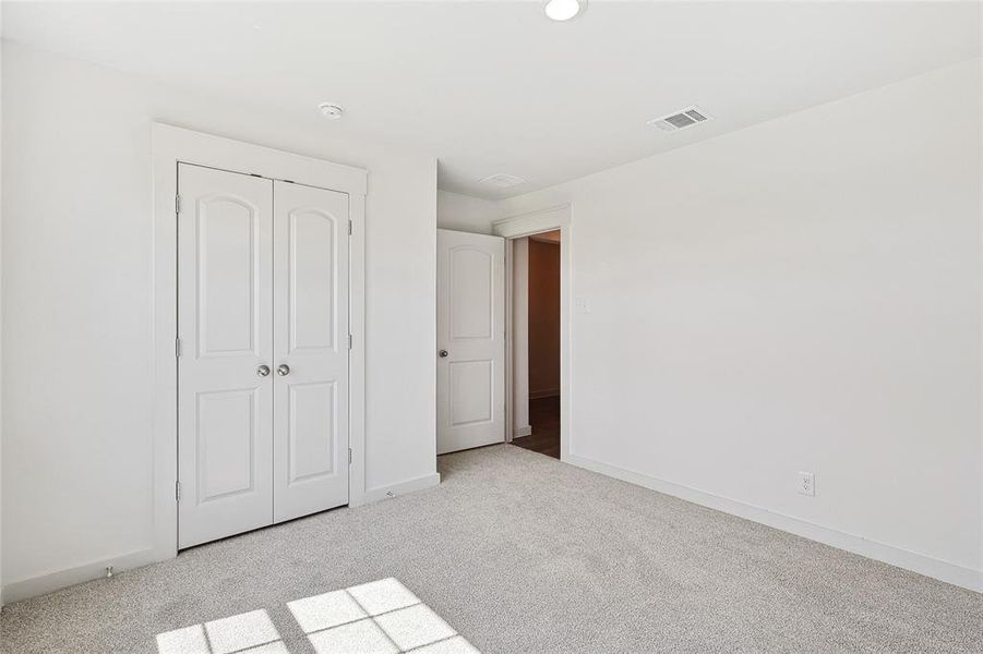 Unfurnished bedroom with light carpet and a closet