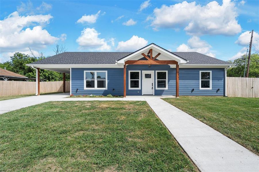 View of front of house with driveway, an attached carport, and roof with shingles