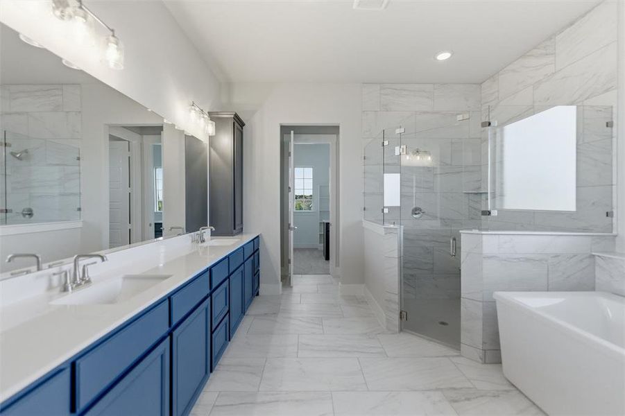 Bathroom with double vanity, a shower stall, light marble finish flooring, a soaking tub, and recessed lighting