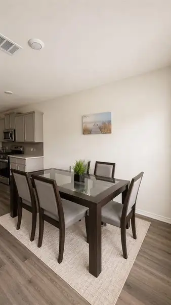 Open-concept dining area featuring wood-finish flooring and light-toned walls Open-concept dining area featuring wood-finish flooring and light-toned walls
