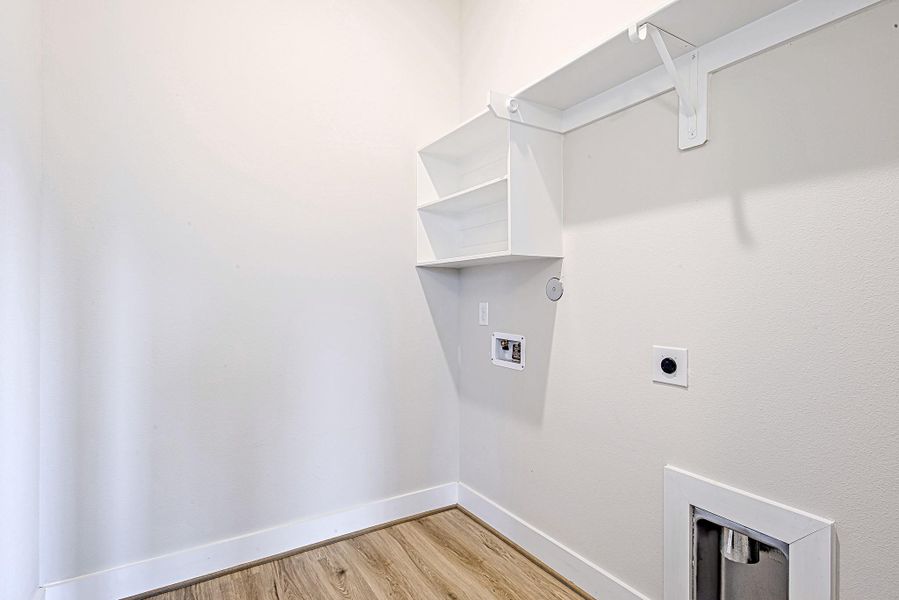 Tucked away for convenience, the laundry room is equipped with storage shelving and ready for full-size washer and dryer hookups.