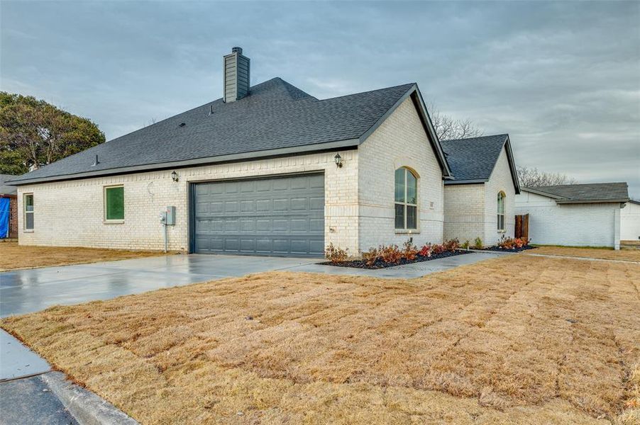 View of property exterior featuring a garage and a lawn