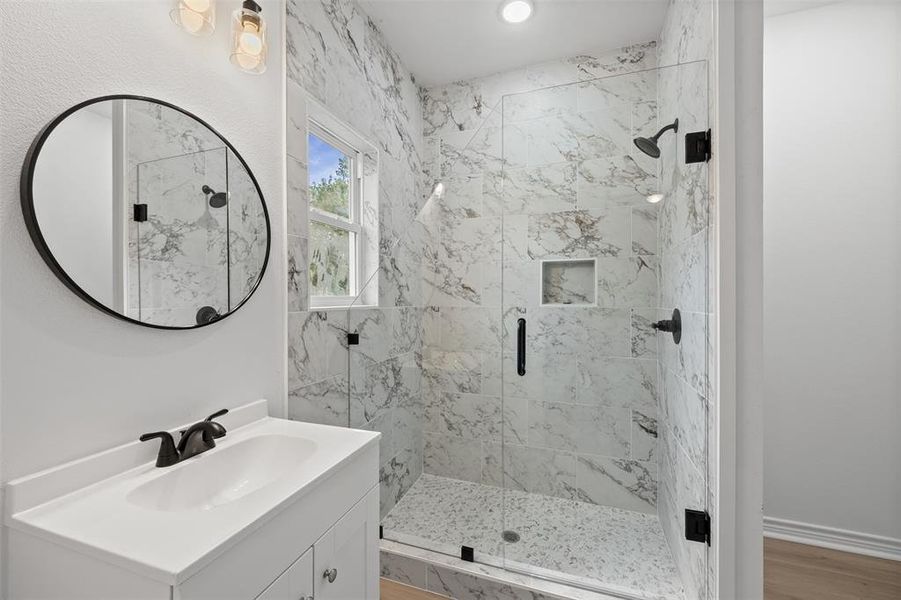 Bathroom featuring vanity, a marble finish shower, and light wood-type flooring