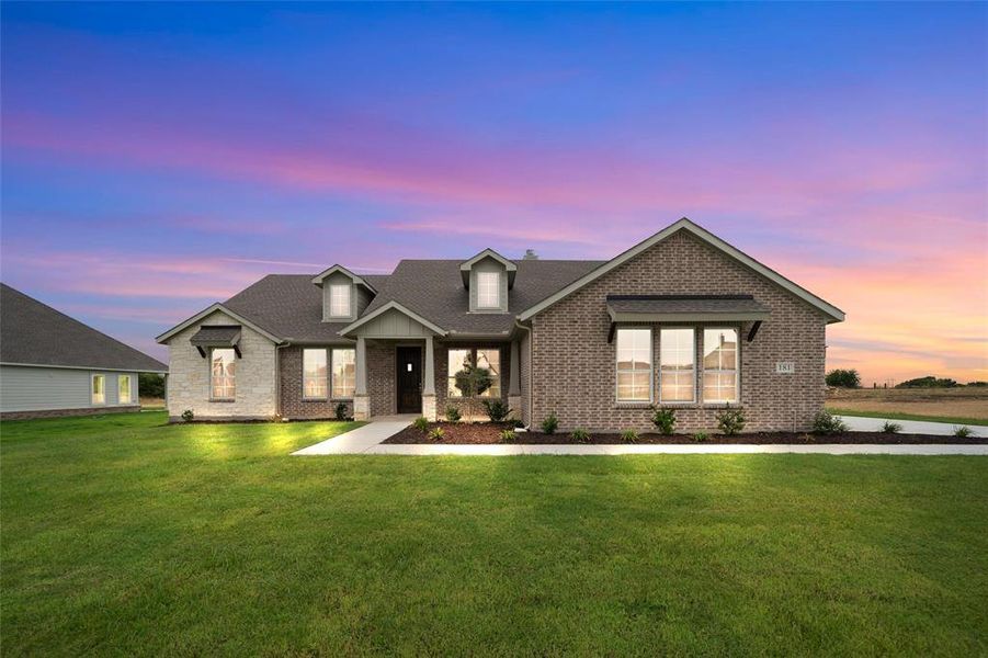 View of front of home featuring brick siding, a yard, and a shingled roof