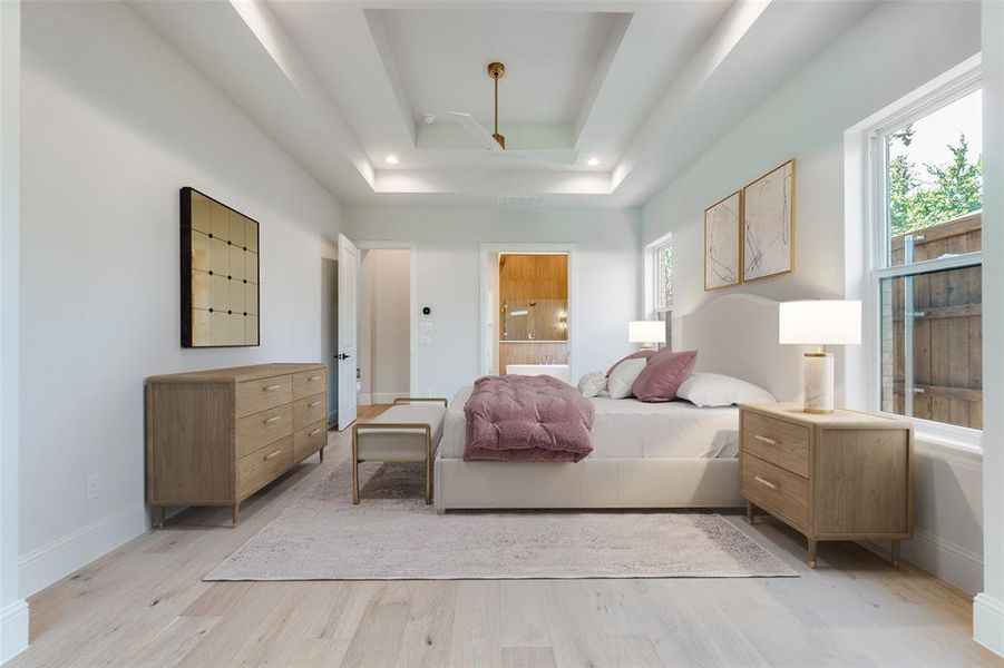 Bedroom with light wood-type flooring, a raised ceiling, and ensuite bathroom Bedroom with light wood-type flooring, a raised ceiling, and ensuite bathroom