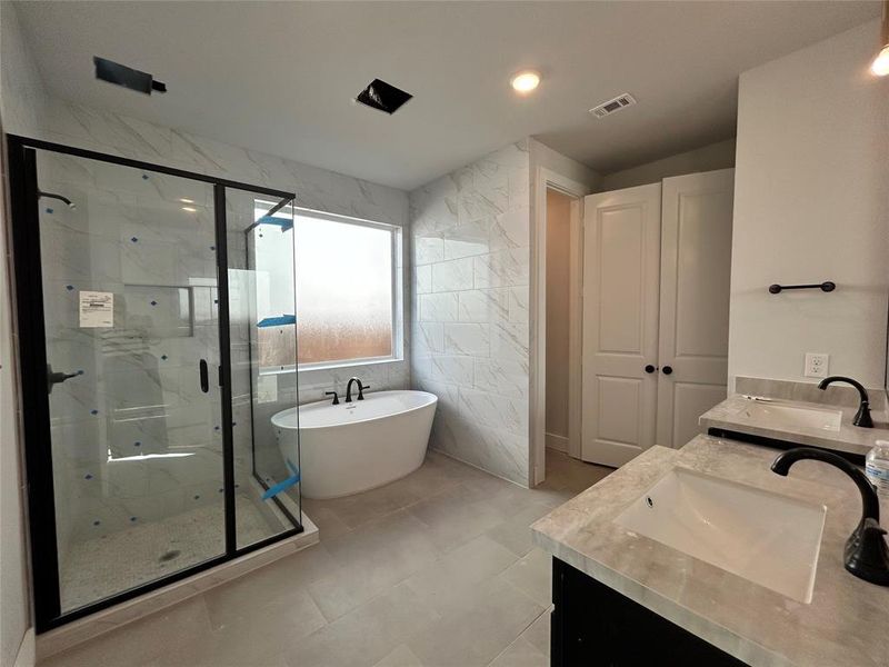 The primary bathroom features sleek, modern design with clean lines, a large walk-in shower, and polished stone countertops, creating a spa-like atmosphere.