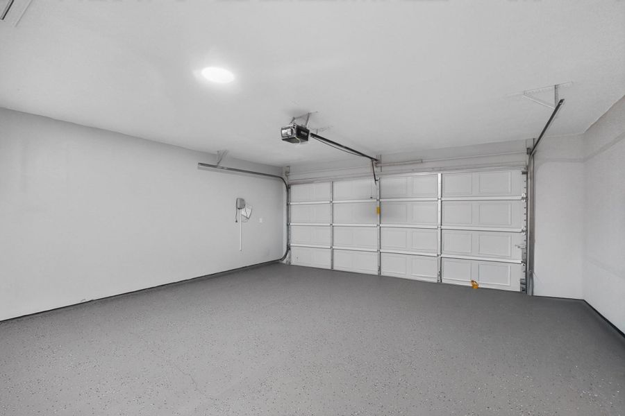 An immaculate finished garage features a durable epoxy-coated floor and overhead motorized door system.