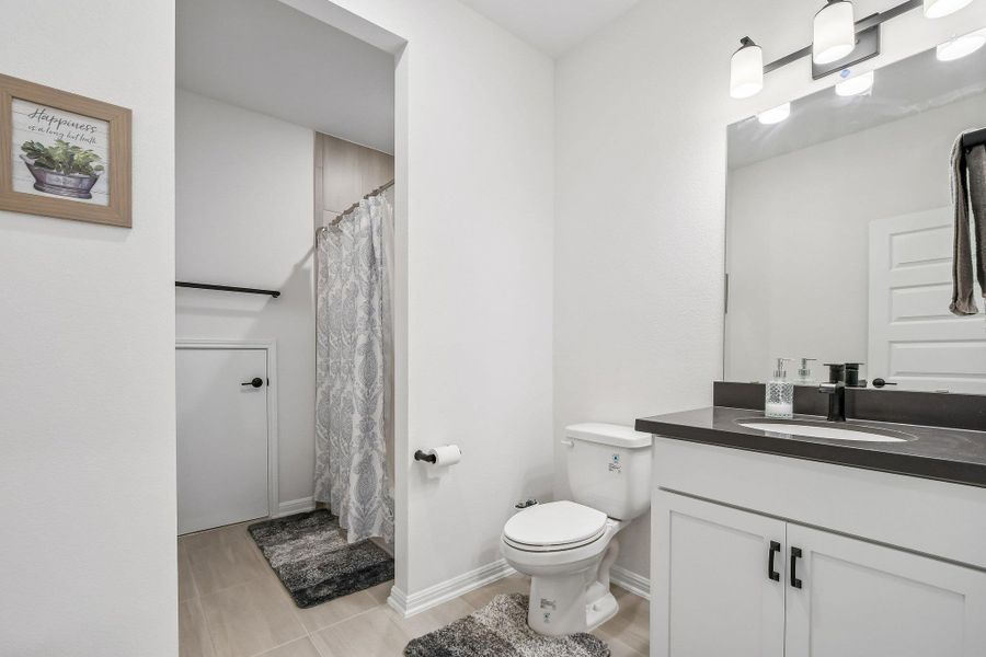 Functional full bathroom featuring a shower, toilet, and vanity with ample counter space.