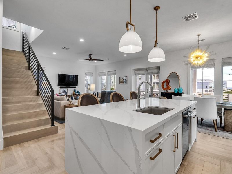 From this angle, the seamless flow of the kitchen truly shines. The design effortlessly connects to the dining and living areas, with the wrought-iron stair railing adding elegance and style. Whether cooking, hosting, or unwinding, this space embodies everyday luxury with coastal ease. From this angle, the seamless flow of the kitchen truly shines. The design effortlessly connects to the dining and living areas, with the wrought-iron stair railing adding elegance and style. Whether cooking, hosting, or unwinding, this space embodies everyday luxury with coastal ease.