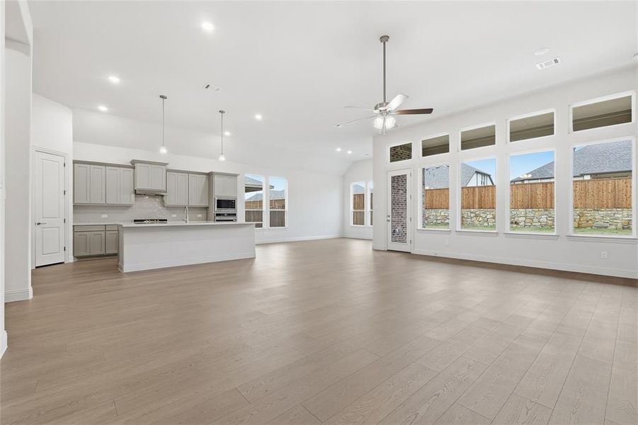 Unfurnished living room featuring light wood-style floors, vaulted ceiling, a ceiling fan, and recessed lighting